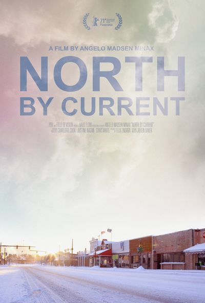 Photograph of a main street of a small town taken in the cold winter daylight. Snow covers the street and sidewalks as the sun shines and illuminates the sky. An american flag waves over a small business building. Some text about the film including the title, director, producer and distributor info is positioned on the top half of the poster with the sky in the background.