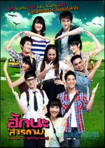 Romantic comedy film poster which features 9 Thai teenager characters in a group pose, forming one large heart with their hands. At the center of the heart, one teenage character poses on their own, making a rock-and-roll hand formation. The characters have fair skin and exaggerated blush, and they all give their own stylized cheeky smiles. The edited and vignetted background contains highly saturated grassy fields, with a bus and a cow peeking out from behind. All of the text, written in a colourful bold font, is in Thai.