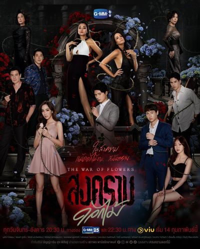 A group of people pose dramatically looking at the camera while standing at various heights across some kind of stone monument. They are all dressed up in fancy clothes. Scattered in and around the people are numerous bouquets of blue lilac-coloured flowers.