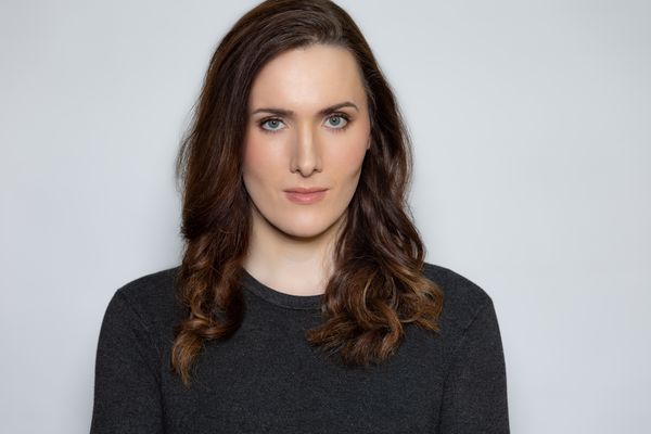 Portrait of Abigail Thorn in a studio with a clean backdrop and high quality lighting. Abigail has fair skin, dark brown medium-length hair blue-green-hazel eyes.